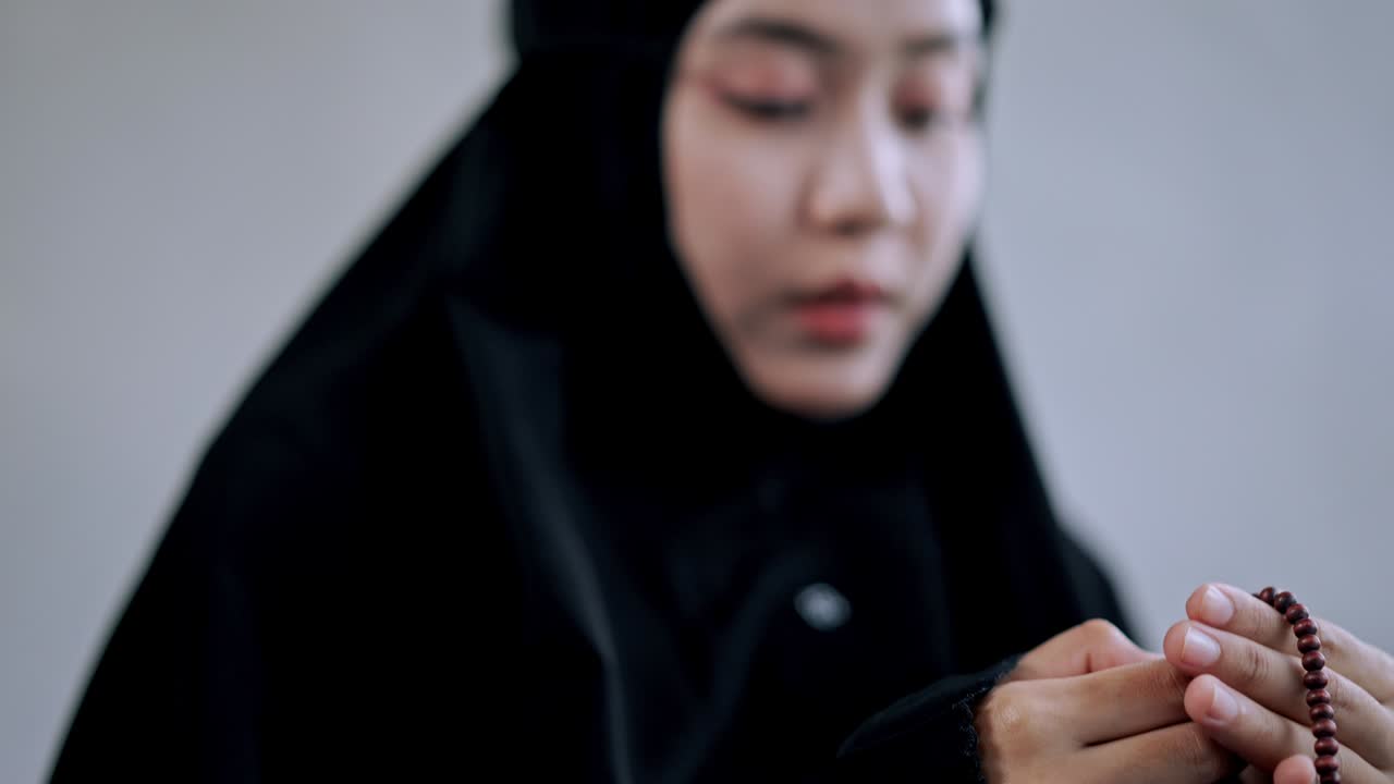 젊은 이슬람 여성 은 기도 할 때 구슬 을 사용 한다