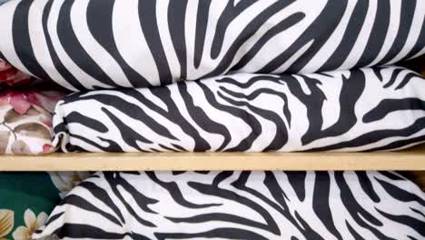 Colorful animal print cushions displayed in a wooden shelf at textile store