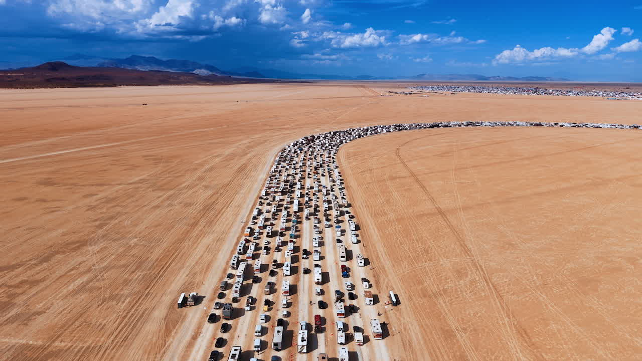 Vast desert crossed by the road stuck with cars and campervans. Amazing azure sky with fluffy clouds at backdrop. Aerial view