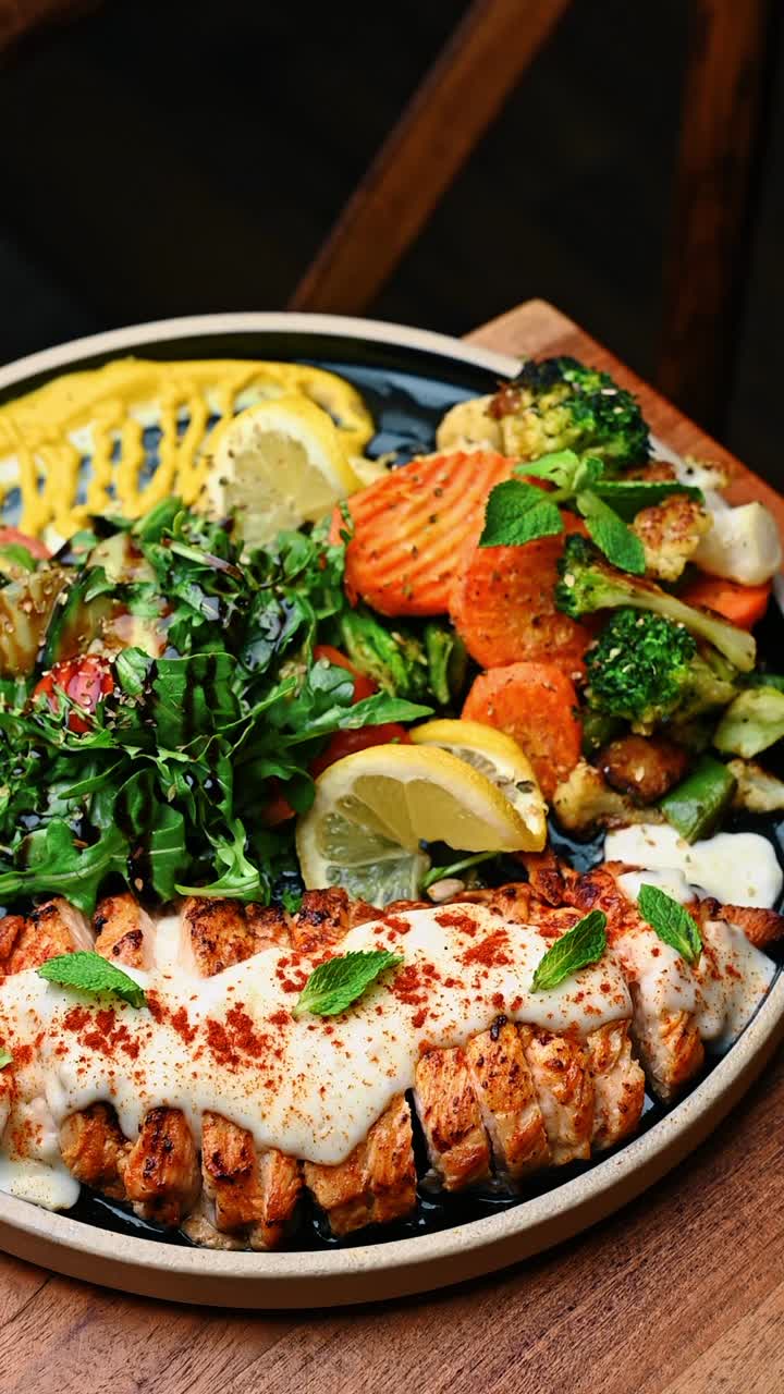 Gesundes Lachs-Abendessen mit gebratenem Gemüse und frischem grünem Salat. Gegrillte Lachsfilets mit weißer Soße und Paprika, serviert mit Brokkoli, Karotten und Balsamico-Salat.
