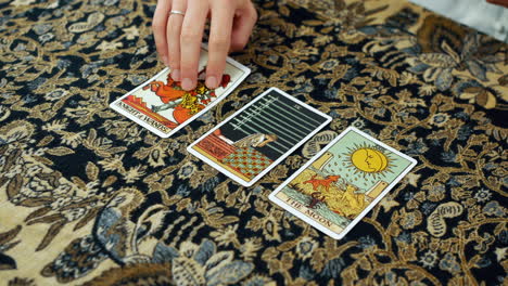 a mystic woman giving a tarot reading with the knight of wands the nine of swords and the moon cards