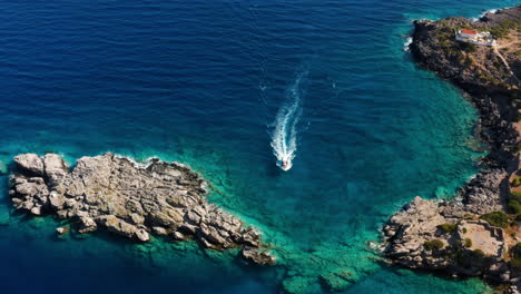 speedboat cruising at turquoise blue sea between outcrops near loutro in crete, greece