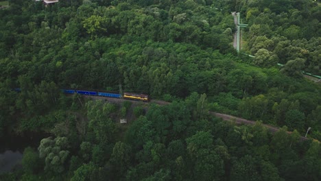 train hauling coal wagons moves slowly through green forestry aerial