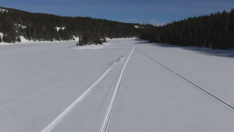 drone follows two snowmobiles across a frozen lake in colorado