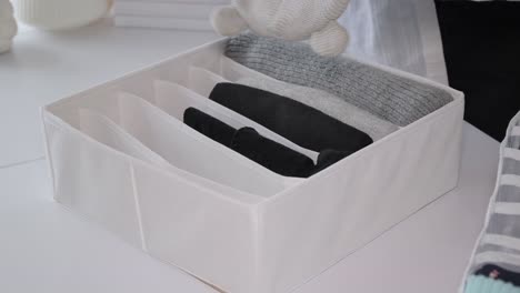 minimalist storage and arrangement in the closet womens hands carefully fold clothes into a basket womens hands carefully fold clothes into a basket the concept of cleaning cleaning cluttering organizing space