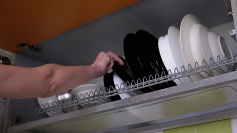 woman opens door of the cupboard with kitchenware drying rack. 4k
