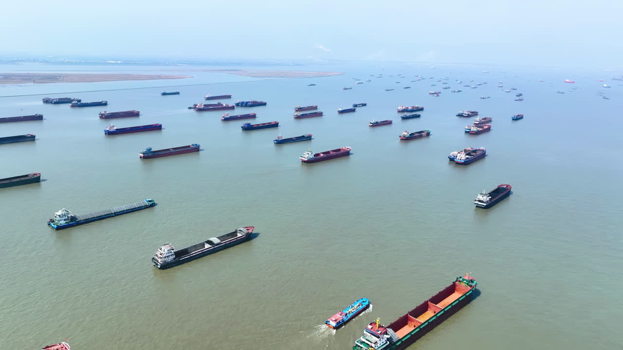 Multiple dry cargo vessels ships anchored waiting for port entrance to loading in industrial port, reflecting slowdown freight traffic, backlog of ships waiting to unload due to imposed trade barriers