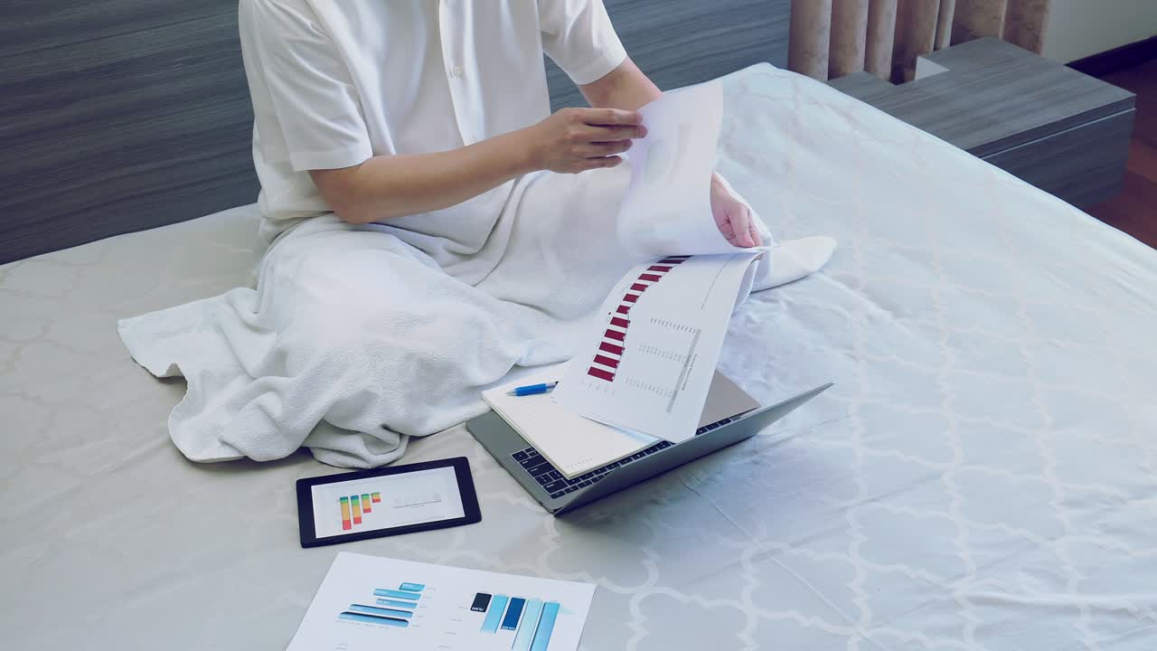 hombre de negocios asiático trabajo con gráfico o informe gráfico en la cama