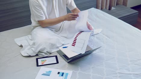 hombre de negocios asiático trabajo con gráfico o informe gráfico en la cama