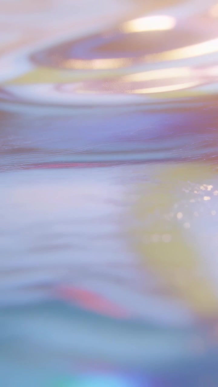 Video vertical: Película iridiscente brillante con remolinos ondulantes, cámara en macro mostrando bandas de color.