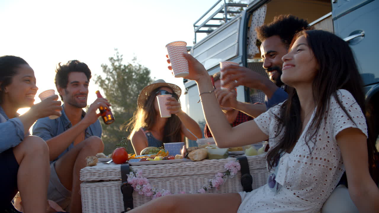 Amici fanno un brindisi a un picnic accanto al loro camper.