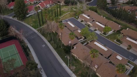 Aerial-drone-footage-of-neighborhood-over-homes-and-tennis-court