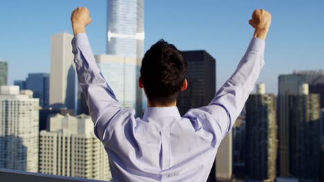 un hombre de negocios asiático celebrando con los brazos en el techo.