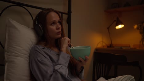 woman eating breakfast in bed while listening to music