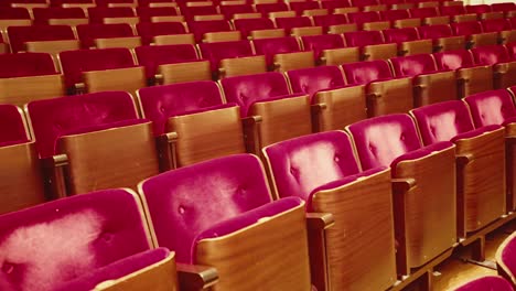 row of vintage red velvet theatre audience seats in empty concert hall