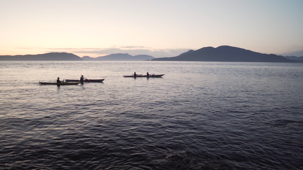 Silhouette Of People Paddling Kayak In The Ocean At Sunrise