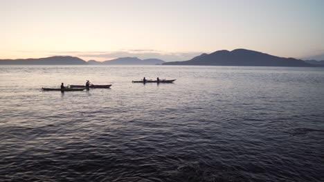 silhouette of people paddling kayak in the ocean at sunrise