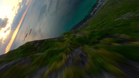 fpv drone flight over rocky and mossy mountains into valley of lofoten fjord in norway - speeding top down flight