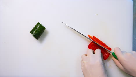 Chef hands slicing sweet red bell pepper on a white cutting board. Beautiful video with soft focus. Healthy food concept.