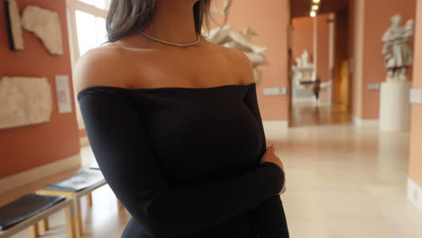 hermosa joven morena elegante con un vestido negro, mirando a su alrededor en el museo del louvre, parís, francia