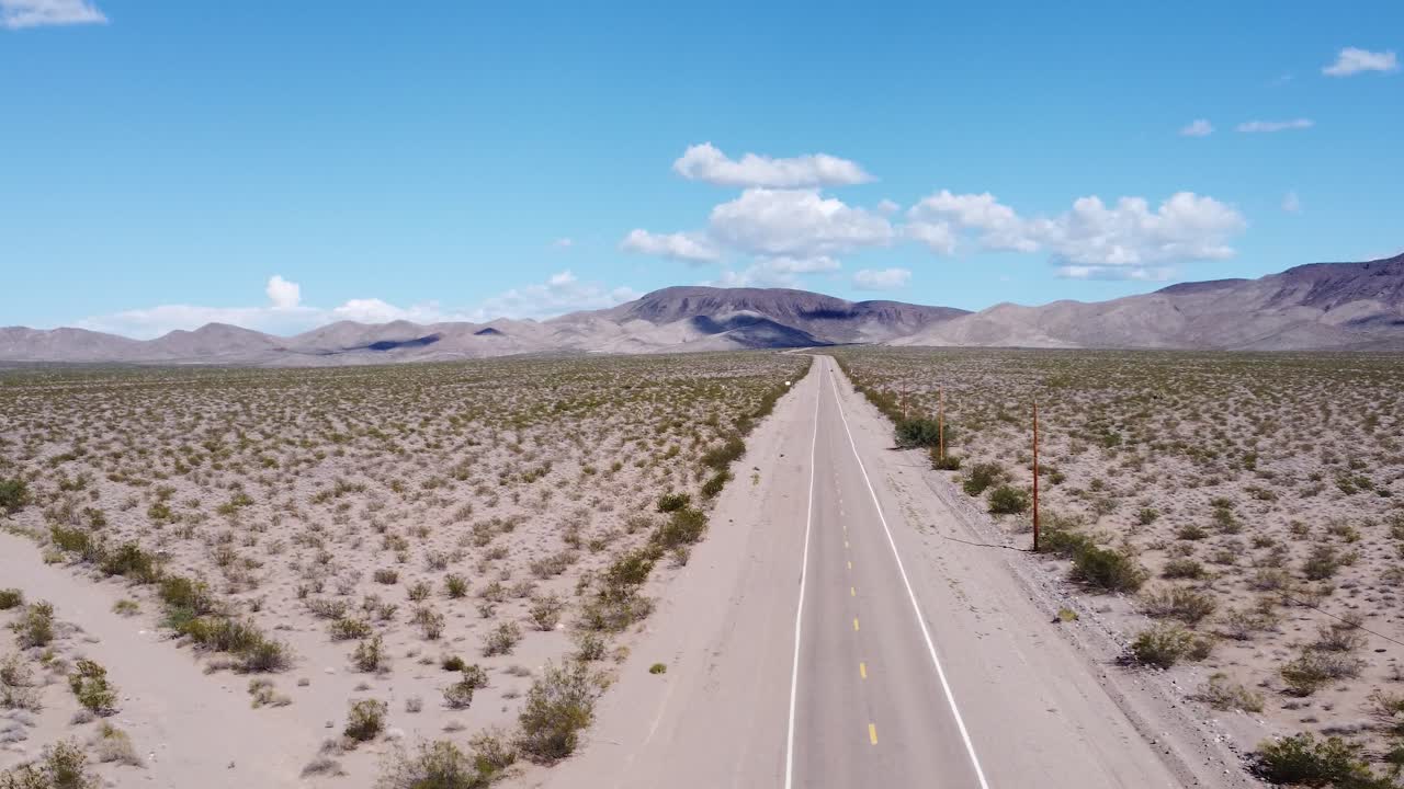 Drone shot of a dirt road leading to a mountain range.