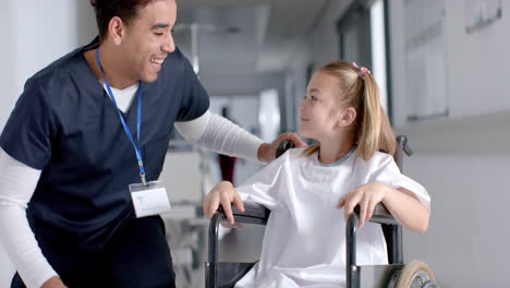 biracial doctor talking to caucasian girl patient sitting in wheelchair in hospital, slow motion