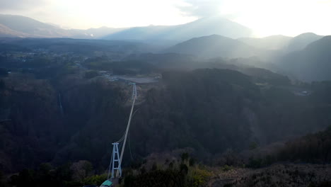 Rotating-drone-shot-of-the-suspension-bridge-Kokonoe-Yume-Otsurihasi,-into-the-sun