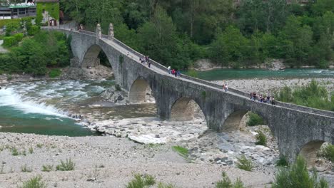 gobbo bridge over trebbia river with people, bobbio in italy