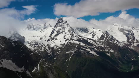 vuelo aéreo a través de nubes montañosas sobre hermosos picos nevados de montañas y glaciares.