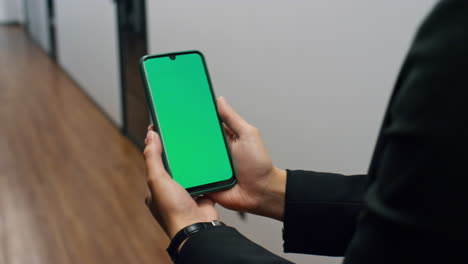 Closeup-hands-holding-smartphone-with-chroma-key-screen.-Manager-walking-office