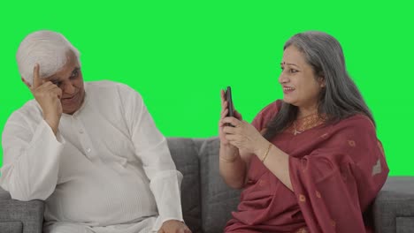 feliz vieja esposa india haciendo clic en la imagen de su marido pantalla verde