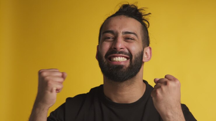 Ritratto in studio di un uomo euforico che celebra buone notizie per aver vinto denaro su sfondo nero 1