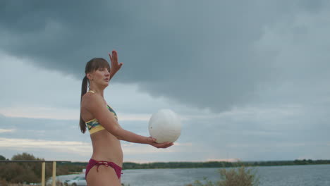 championship of beach volleyball between ladies portrait shot of player serving ball into play sportswoman dressed sporty bikini