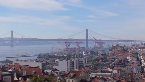 Grúas-Portuarias-A-Lo-Largo-Del-Río-Tajo-Debajo-Del-Puente-Colgante-En-Lisboa,-Portugal,-En-La-Mañana-Del-Cielo-Azul-Brumoso