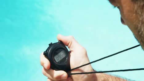 lifeguard looking at stop watch at pool side