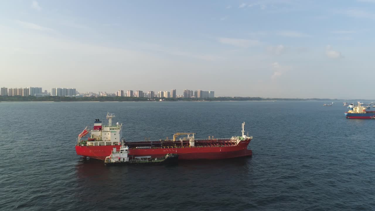 Red Tanker Ship in Harbor with Cityscape