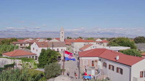 old stone entrance with flag waving in wind at medieval village nin, croatia