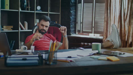 tired businessman putting feet on table and listening music in headphones