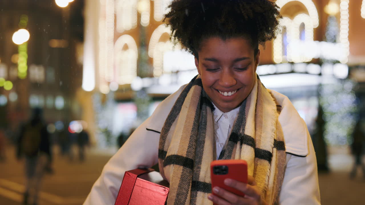 Woman with gift and cellphone at night