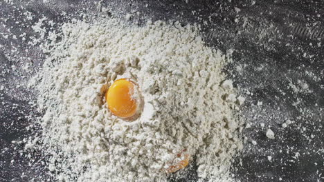 yolks fall on flour creating a splash in slow motion with a table top shot