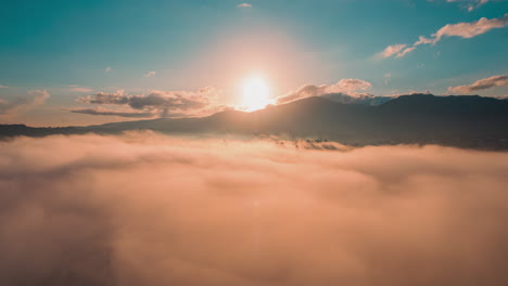 Impressive-view-of-the-sun-rising-over-the-mountains-and-clouds-with-dense-fog-in-the-morning,-stunning-aerial-timelapse-in-the-caribbean