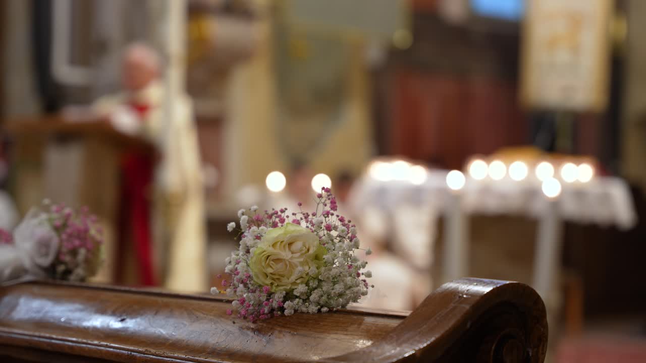 Interior of Catholic church during Holy Communion mass with altar and congregation blurred behind flower bouquet