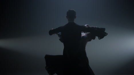 Ballroom-pair-performing-valse-on-stage.-Beautiful-couple-dancing-in-dark-hall.