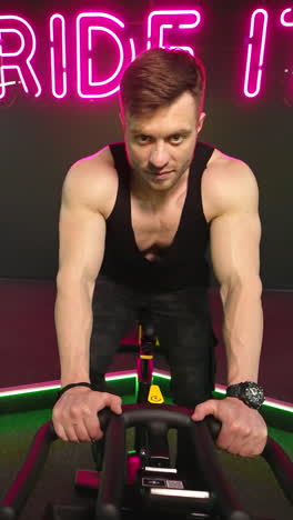 man training on spin bike. front view of man spin legs on smart trainer in gym