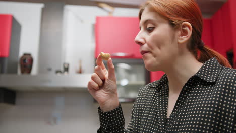happy woman eats sweet cantucci in kitchen