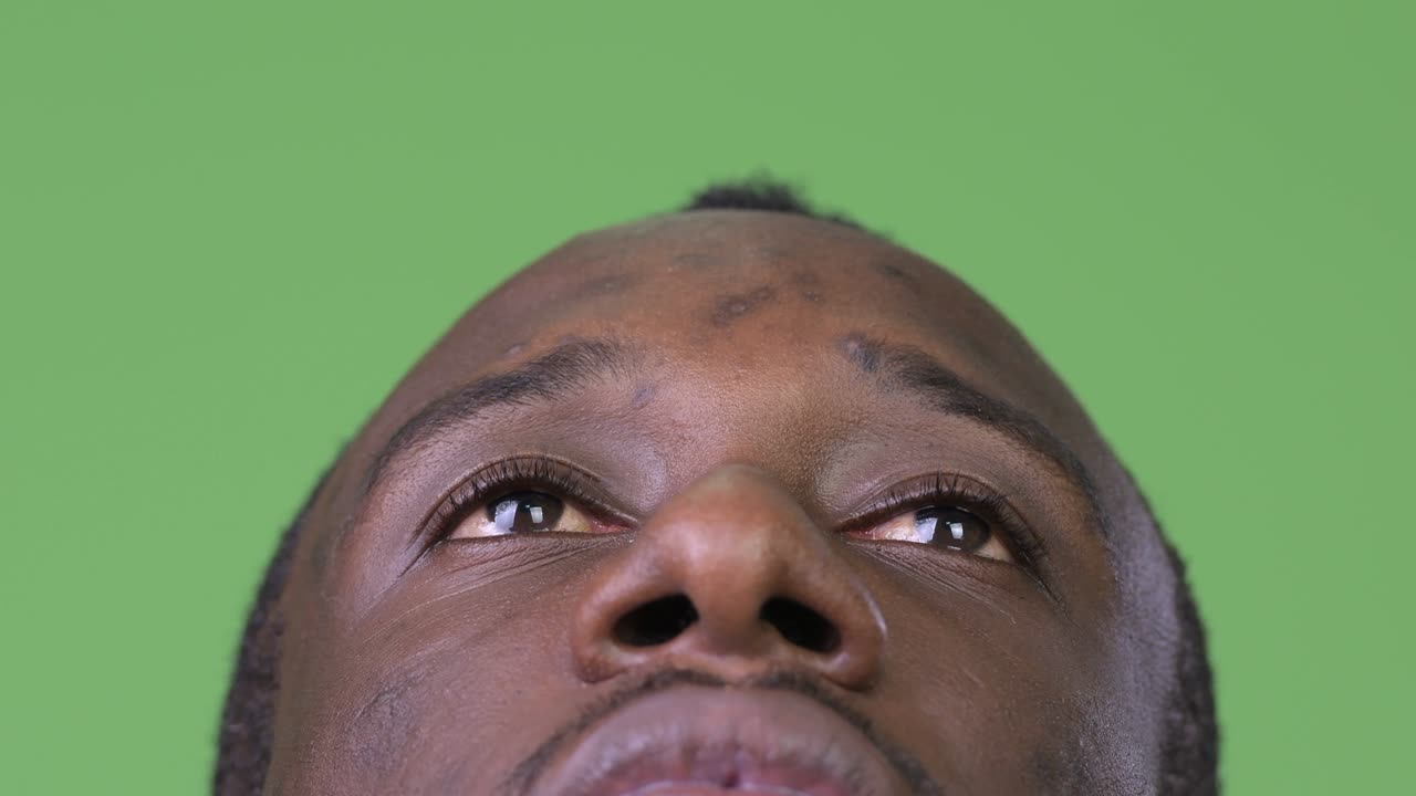 Close up shot of young African man thinking while looking up