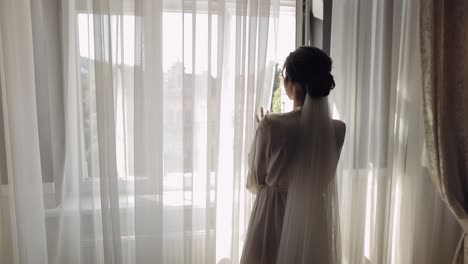 novia en vestido de boudoir caminando hacia la ventana, preparativos de la mañana de la boda, mujer en vestido y velo de noche