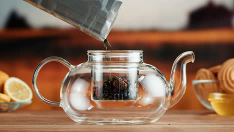 pouring loose leaf tea into a glass teapot
