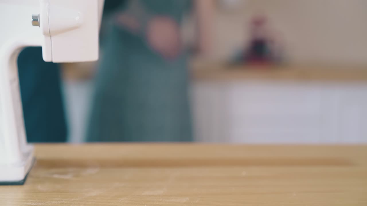 woman carries away bowl of flour from domestic mill on table