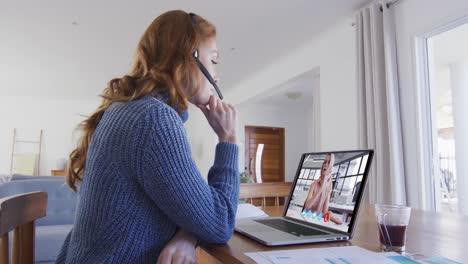 Caucasian-woman-using-laptop-and-phone-headset-on-video-call-with-female-colleague